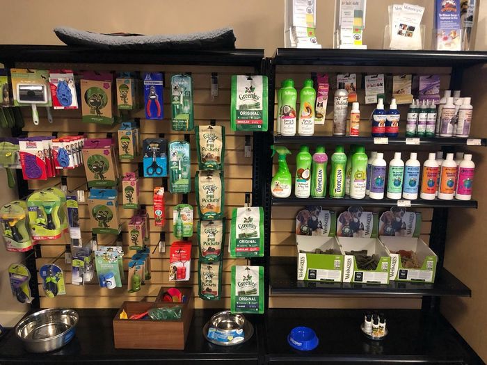 A wall of pet treats, chews, shampoos and care products, with bowls on the shelf below